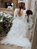 Vestidos de novia con corte princesa y línea A, de tul con volantes, escote cuchara, mangas largas y cola barrida o en pincel.