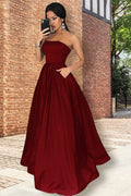 Vestido de fiesta largo strapless color burdeos en corte princesa de satén con bolsillos